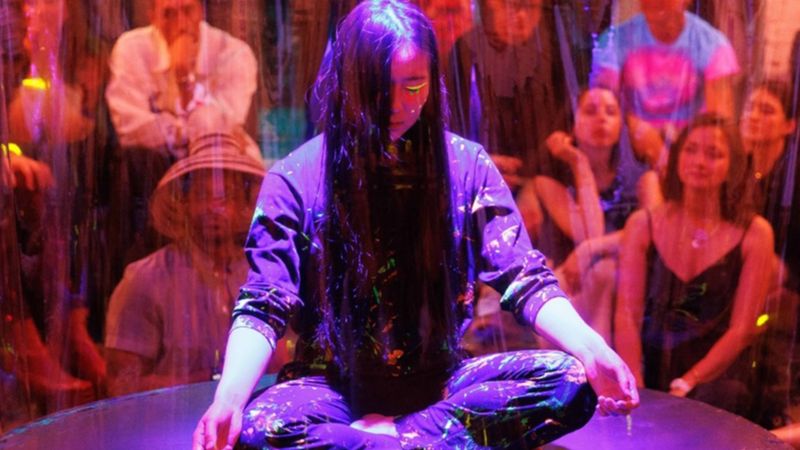An image of Fusilier in a leather vest and a polo standing against a blue wall