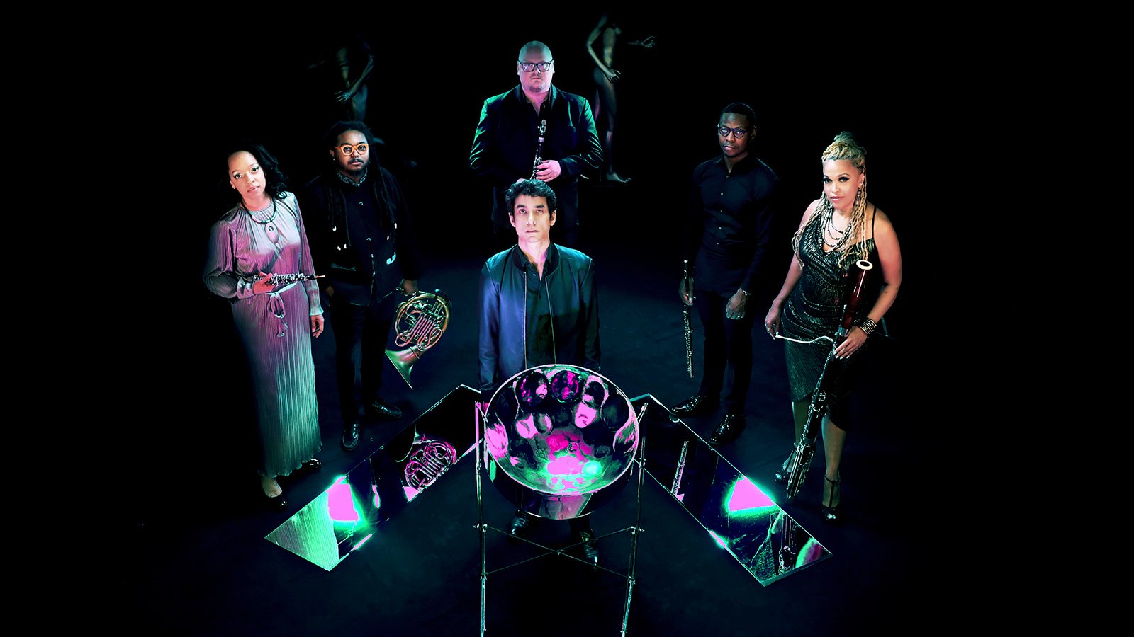 An image of Fusilier in a leather vest and a polo standing against a blue wall