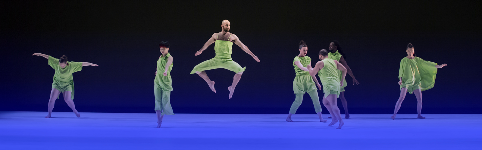 Dancers in green move across a stage