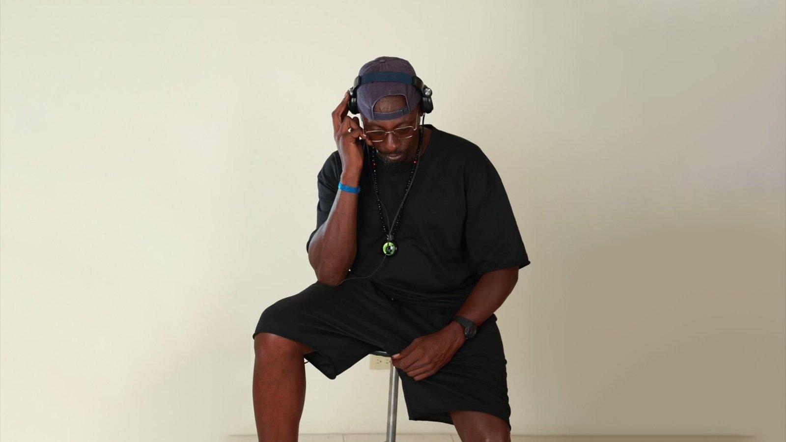 Pete Rock sits on a stood with headphones on