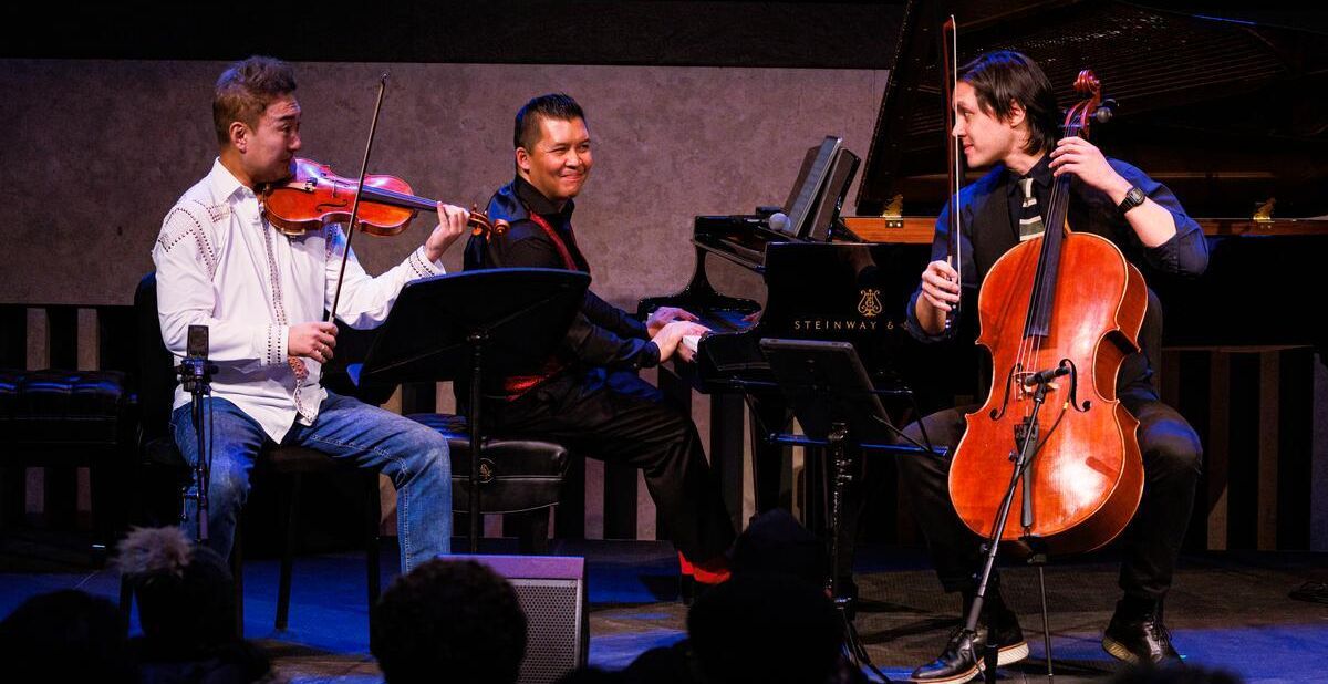 Three men playing piano, violin, and cello