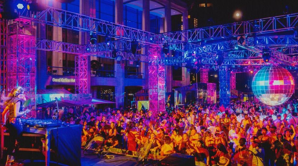 AN audience dances under a 10 ft disco ball