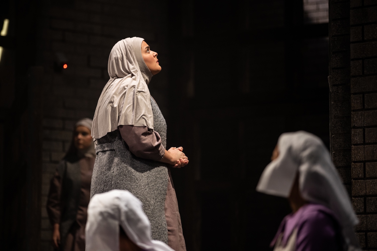 A woman praying with a grey shawl over her head