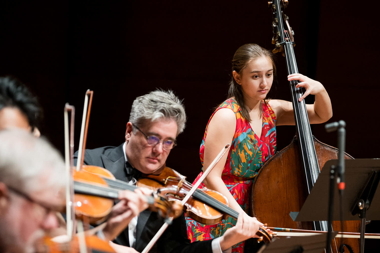 A man in a yellow t-shirt laying on his side in front of a projected version of Hamlet