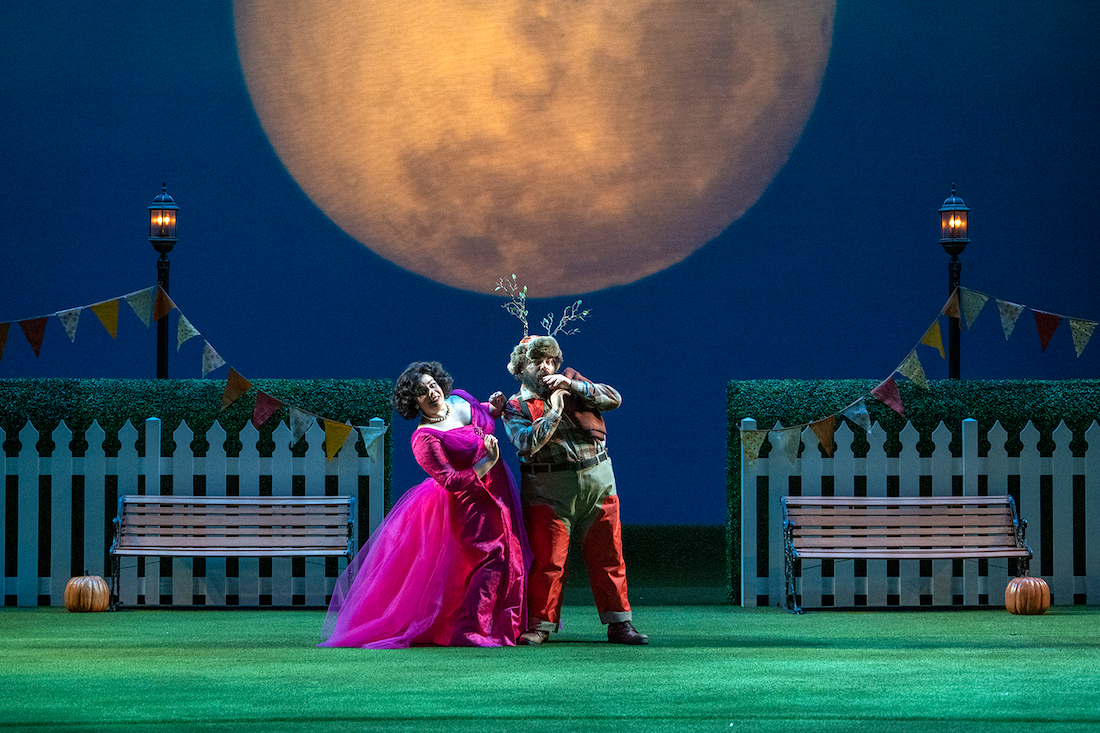 A woman sitting on a plush bench holding a cello