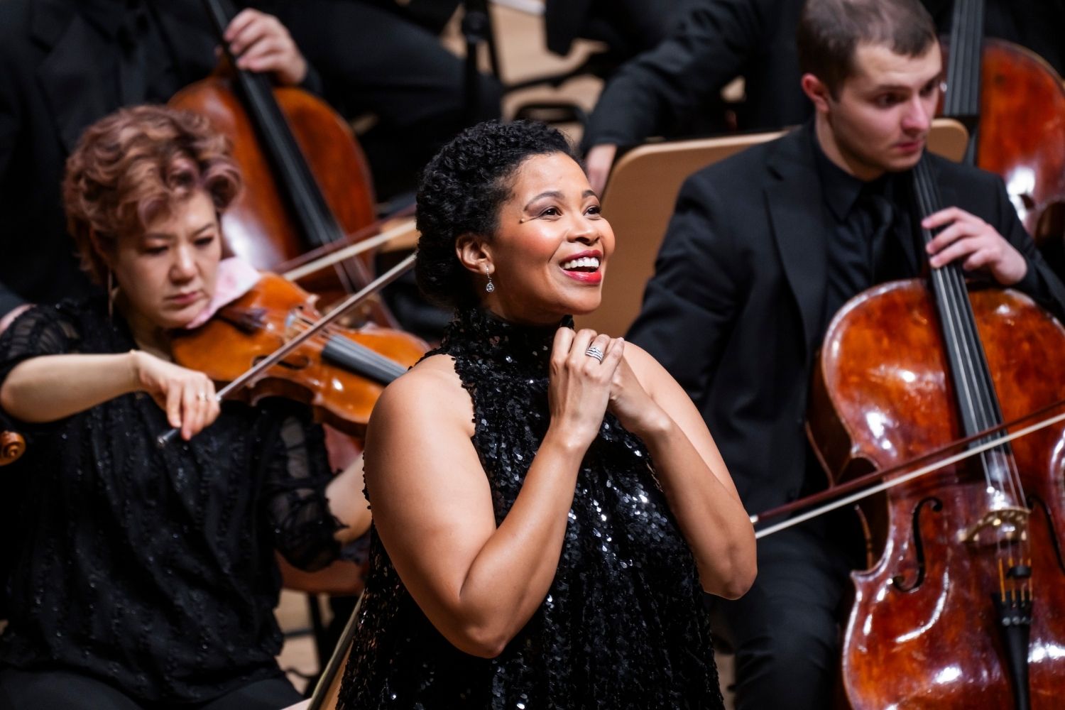 A woman sitting on a plush bench holding a cello