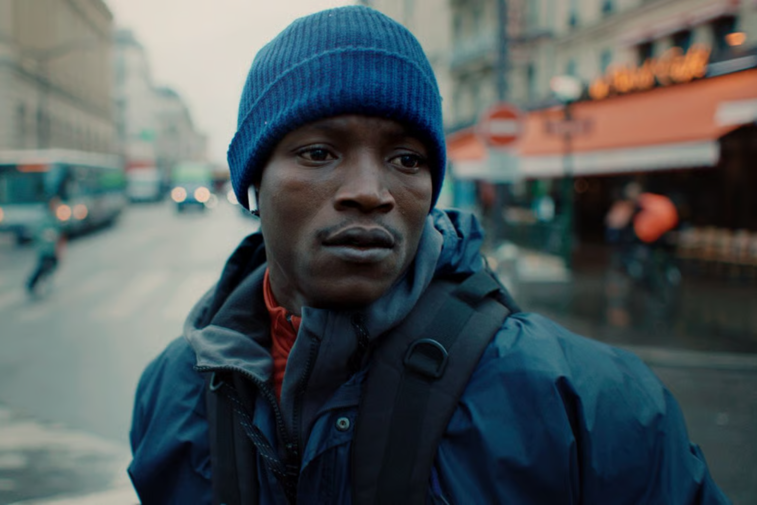 A black man wearing a blue beanie while standing in a city street