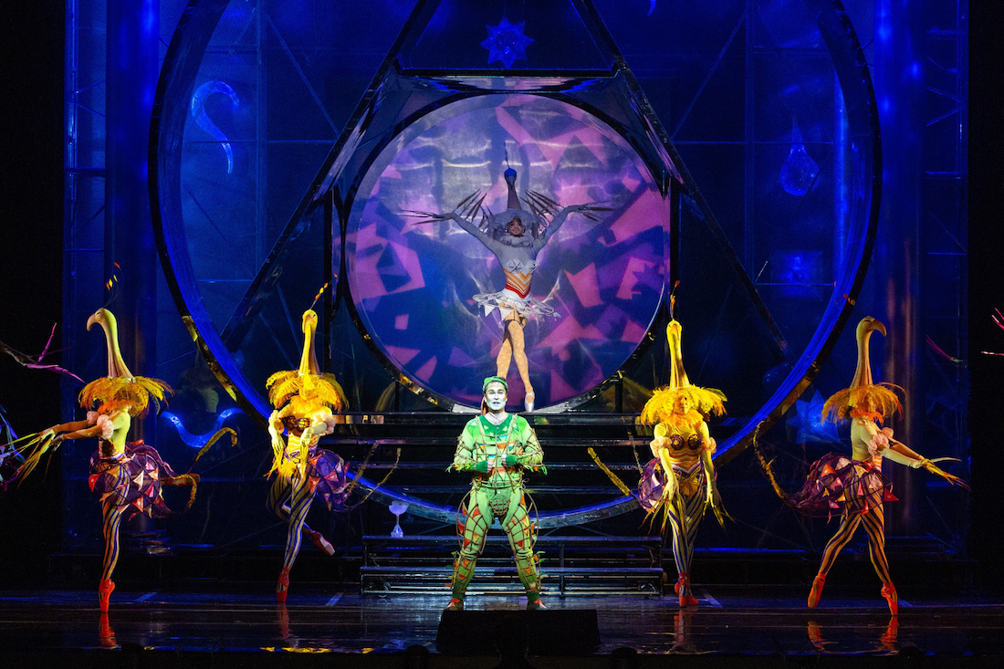 A woman with blonde hair wearing a white dress lying on a marble slab