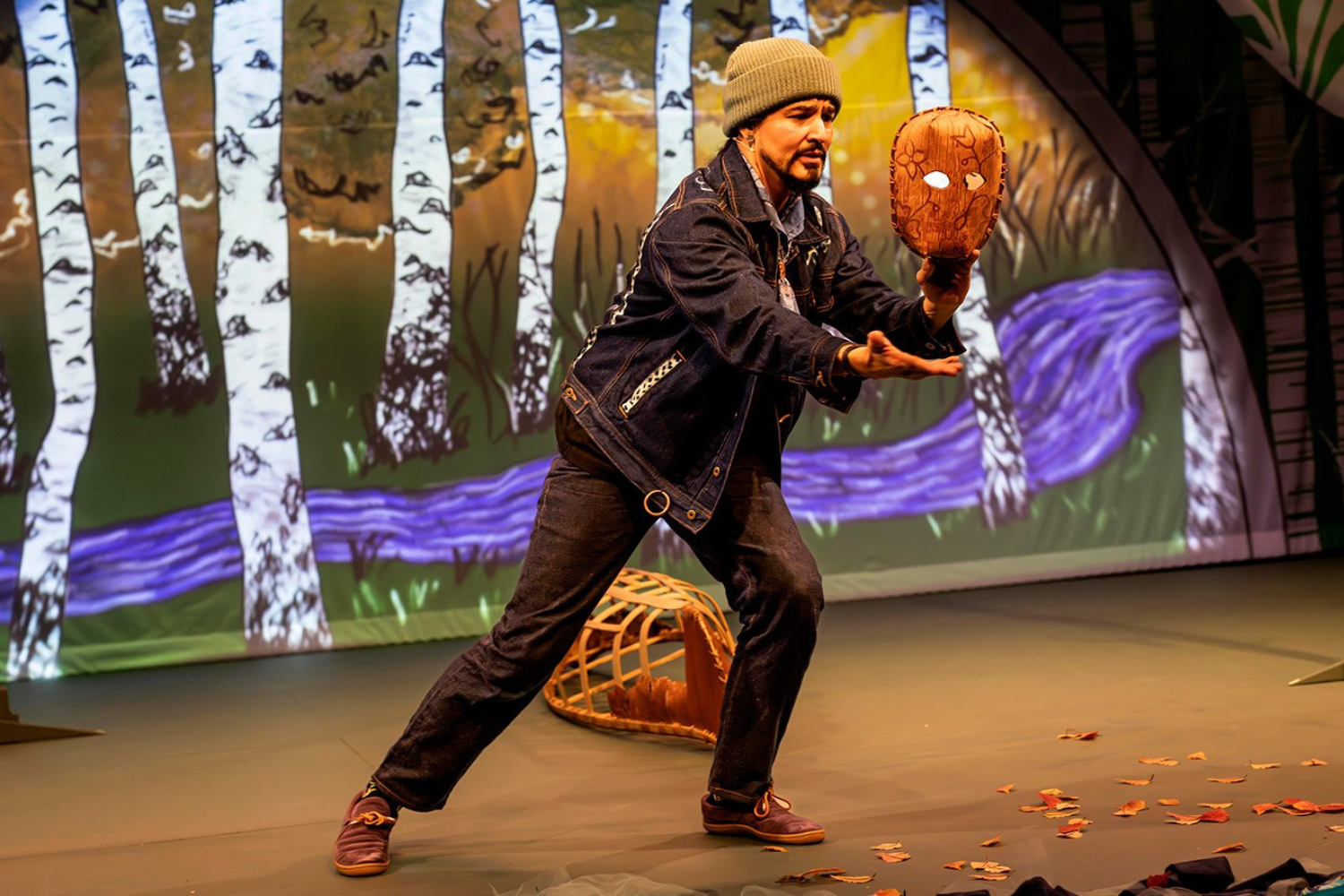 A man in a yellow t-shirt laying on his side in front of a projected version of Hamlet