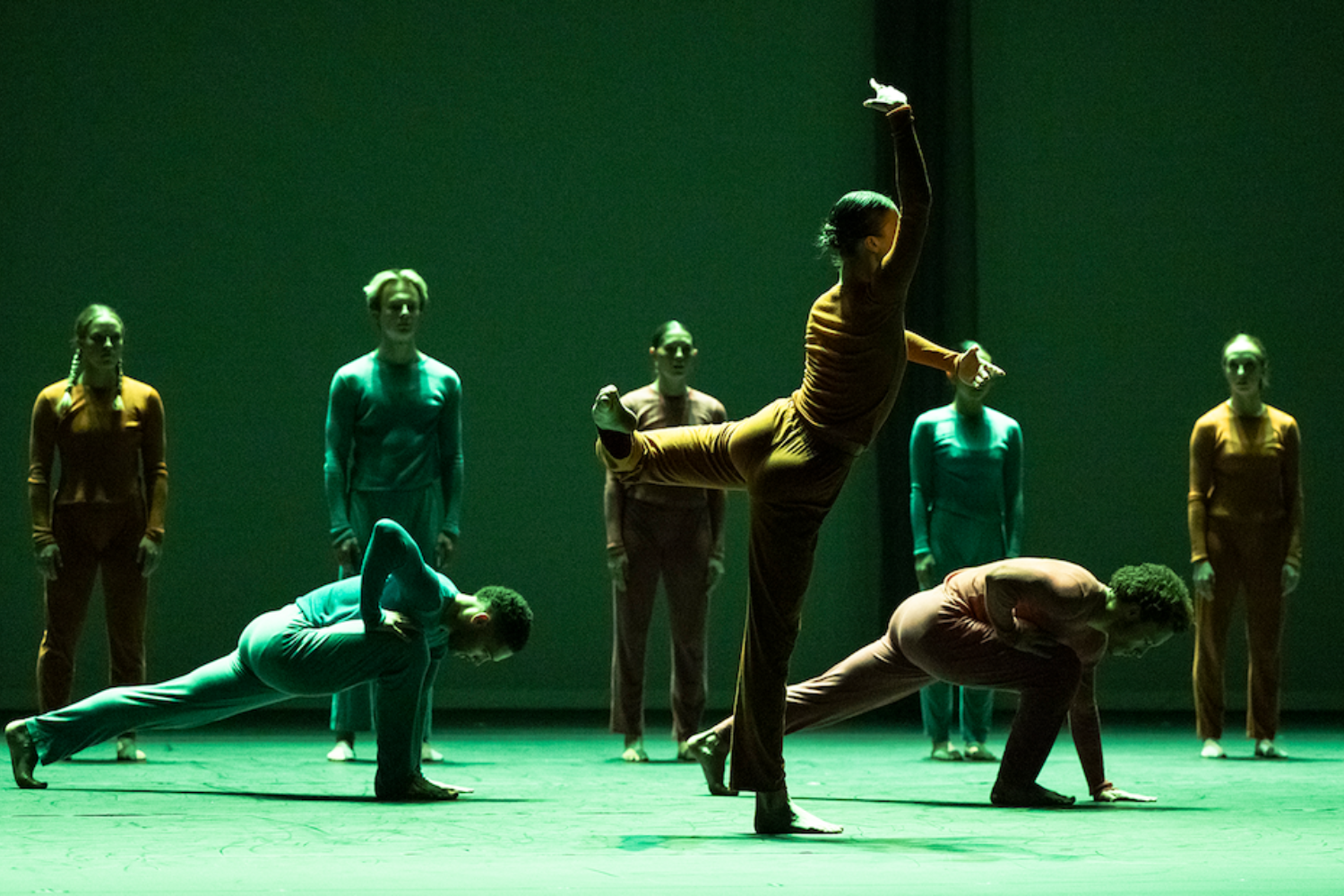 A man in a yellow t-shirt laying on his side in front of a projected version of Hamlet