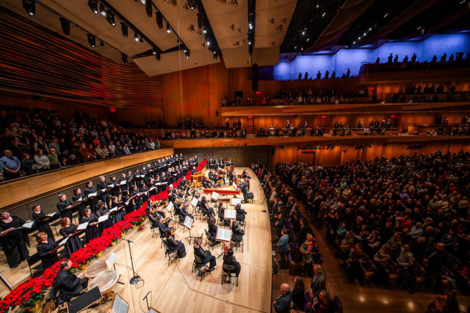 A woman sitting on a plush bench holding a cello