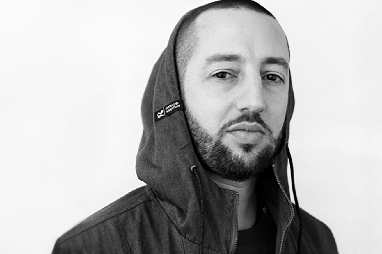 Black and white photo of a man with a buzz cut wearing a hoodie jacket