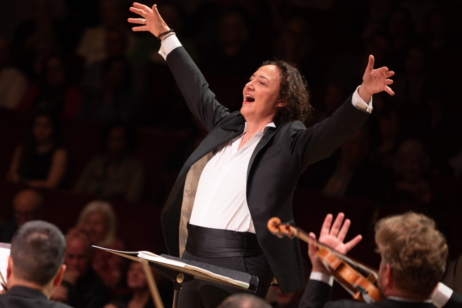 A woman in a black suit conducting an orchestra
