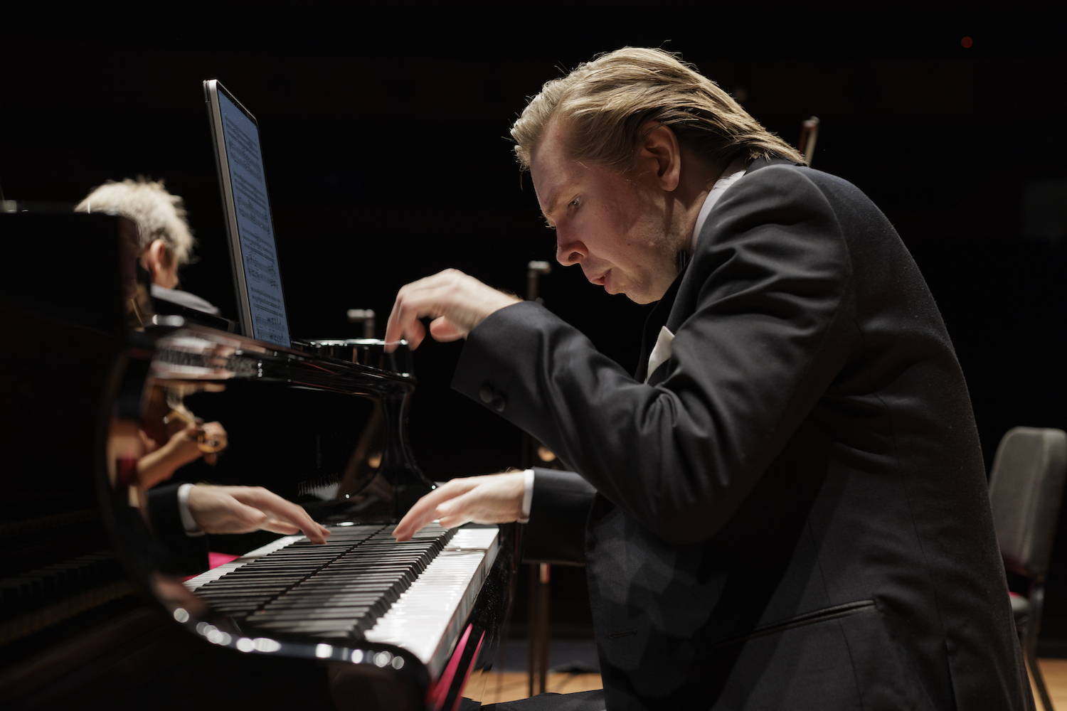 A man in a yellow t-shirt laying on his side in front of a projected version of Hamlet