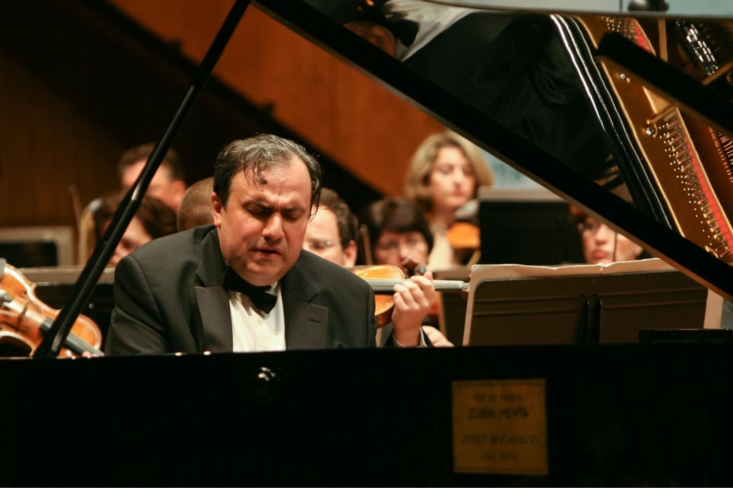 A woman sitting on a plush bench holding a cello