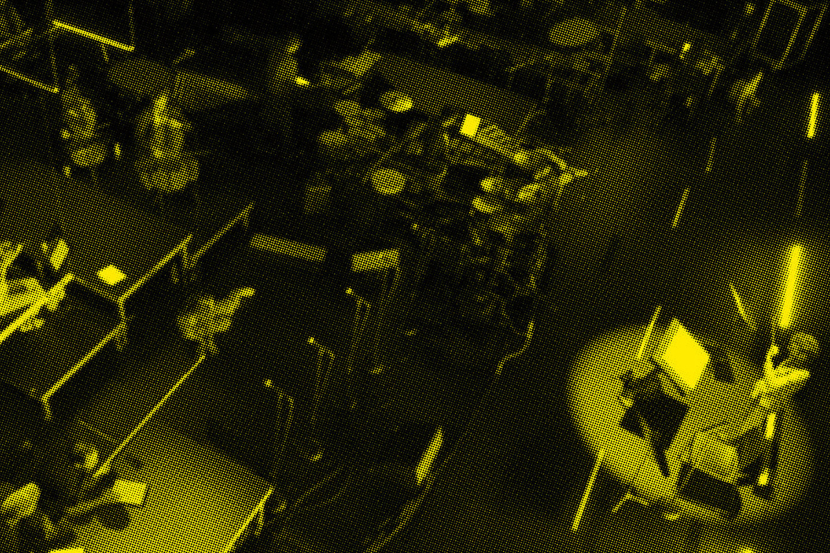 A black and yellow image of a conductor and musicians on stage