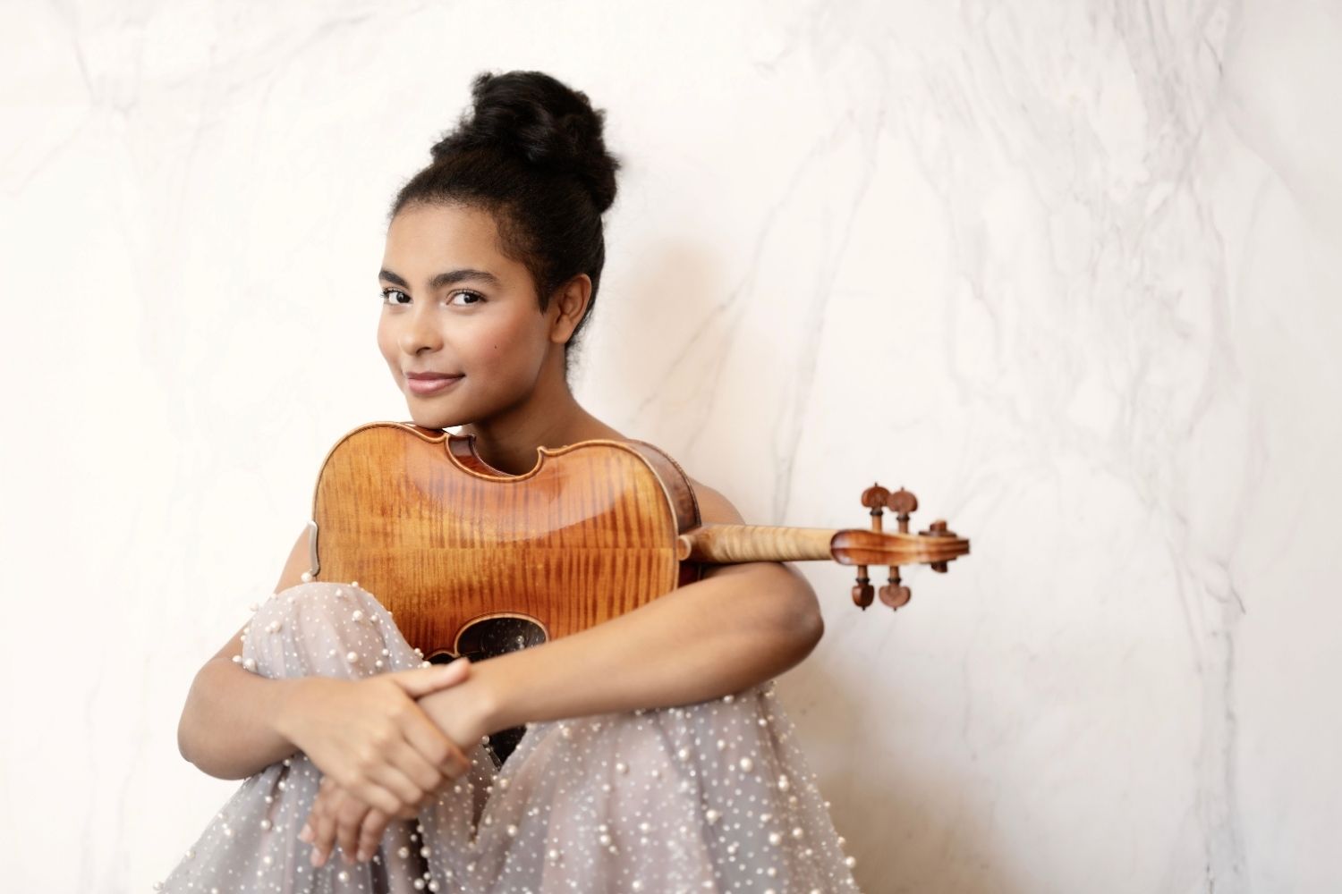 A woman sitting on a plush bench holding a cello