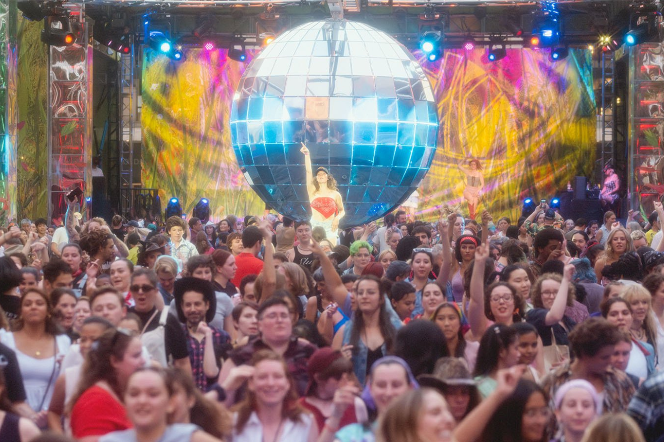 A crowd of people in front of a 10 foot disco ball