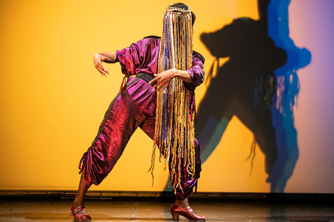 A man in a yellow t-shirt laying on his side in front of a projected version of Hamlet