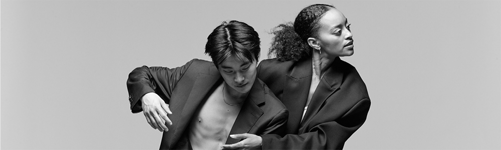 Black and white photo of 2 dancers in motion wearing suit jackets