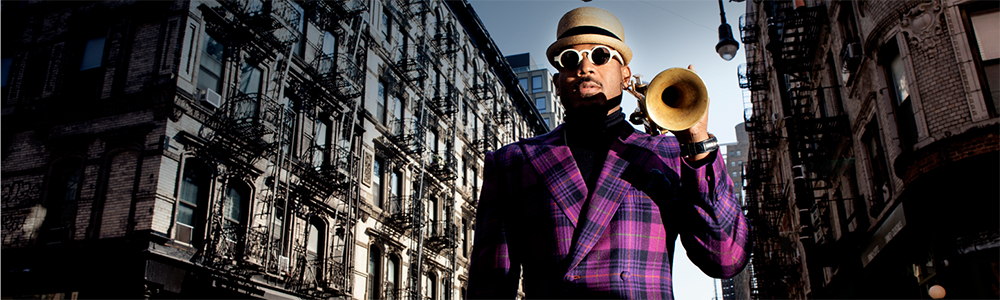 A man holds a trumpet in front of a New York City building facade