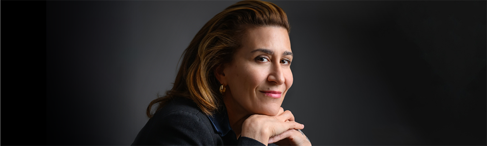 Jeanine Tesori rests her head on her hands and smiles at the camera