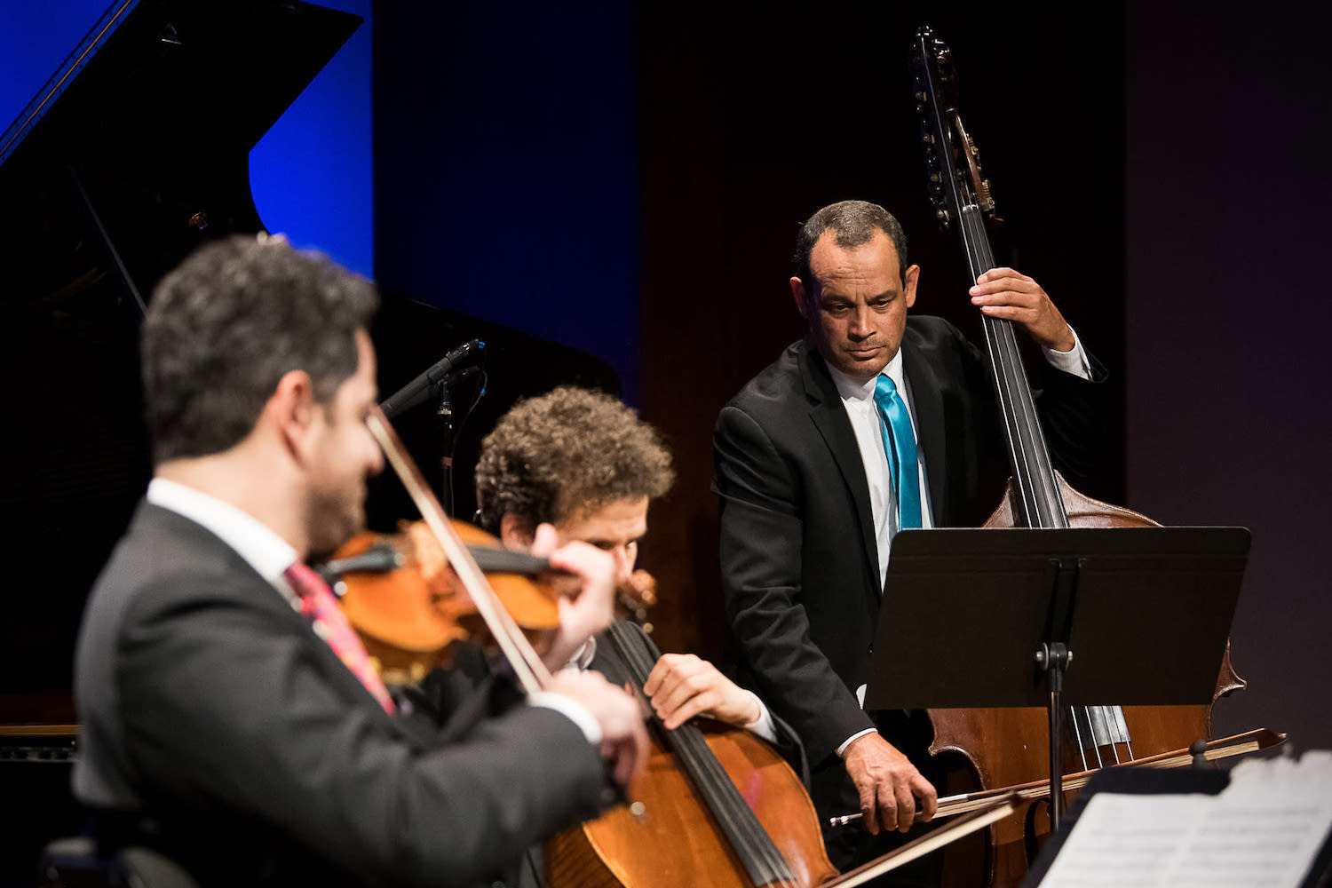 Three men playing violin, cello, and bass