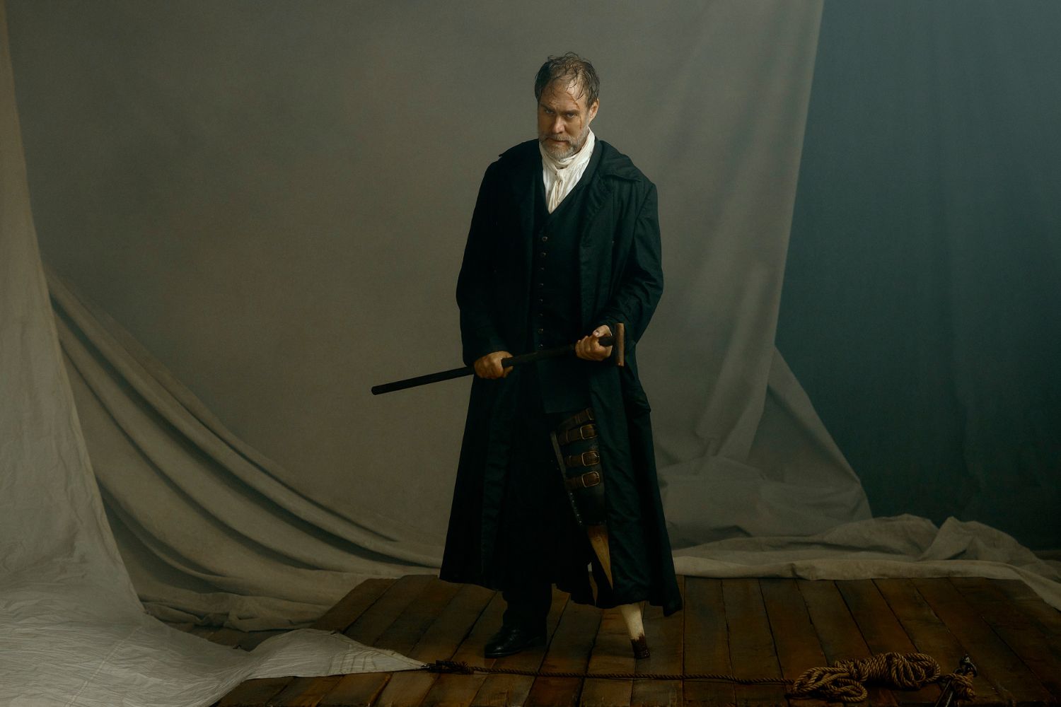 A man in a long black coat holding a cane