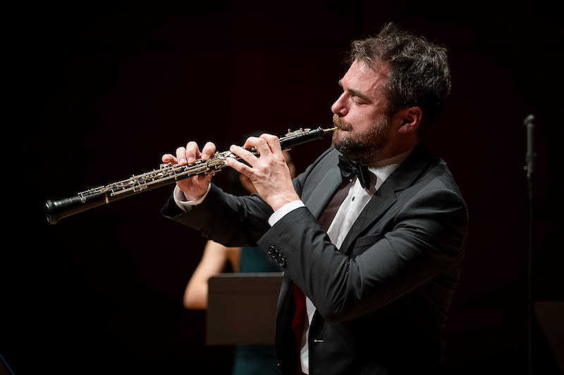 A man in a yellow t-shirt laying on his side in front of a projected version of Hamlet