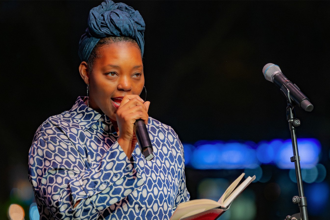 A man in a yellow t-shirt laying on his side in front of a projected version of Hamlet