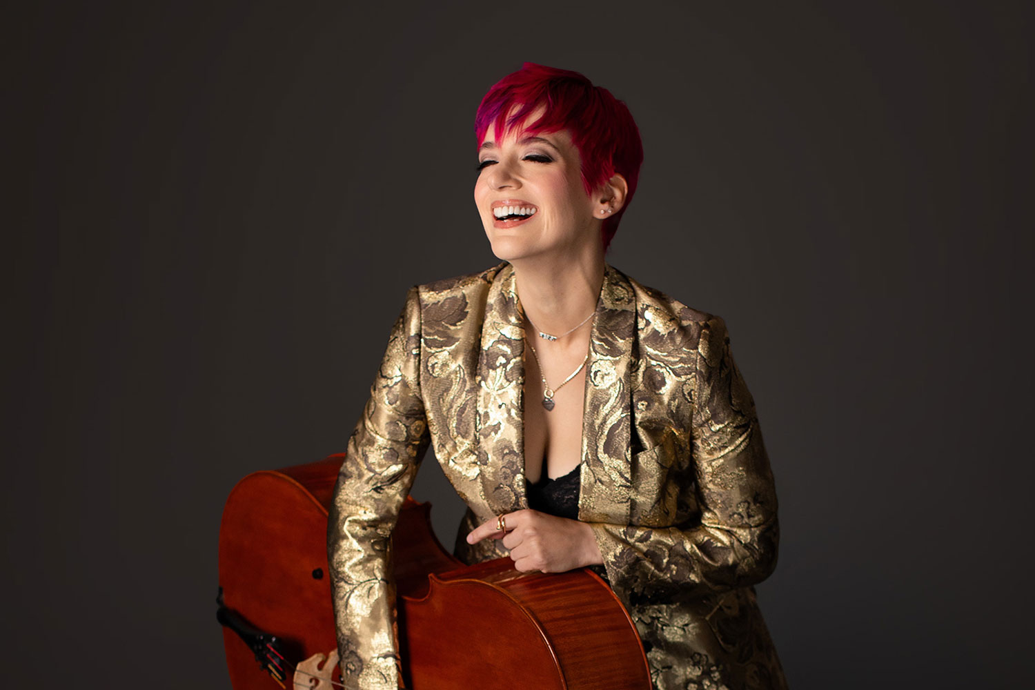 A woman sitting on a plush bench holding a cello