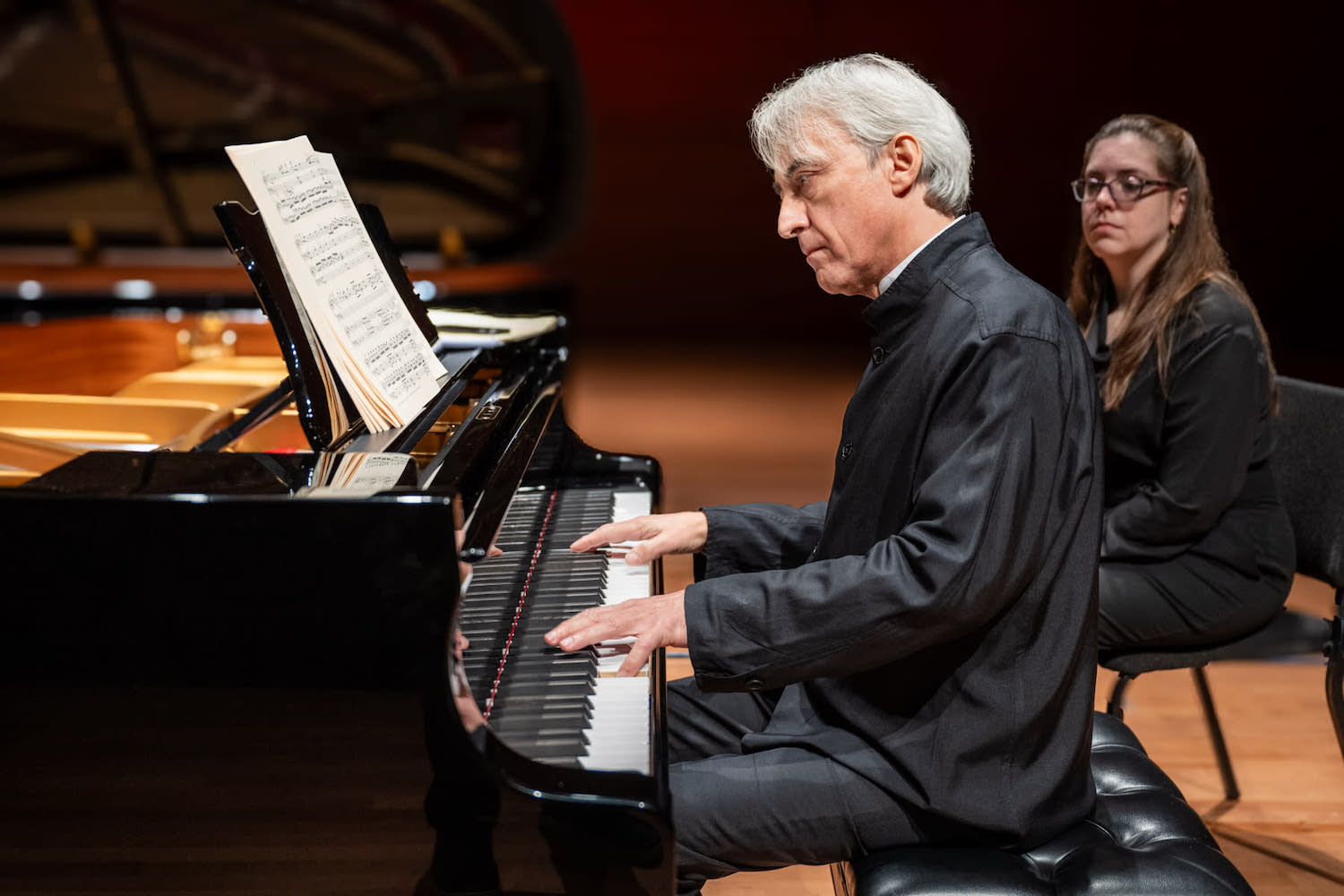 A man in a yellow t-shirt laying on his side in front of a projected version of Hamlet