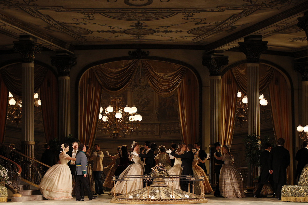 A woman with blonde hair wearing a white dress lying on a marble slab