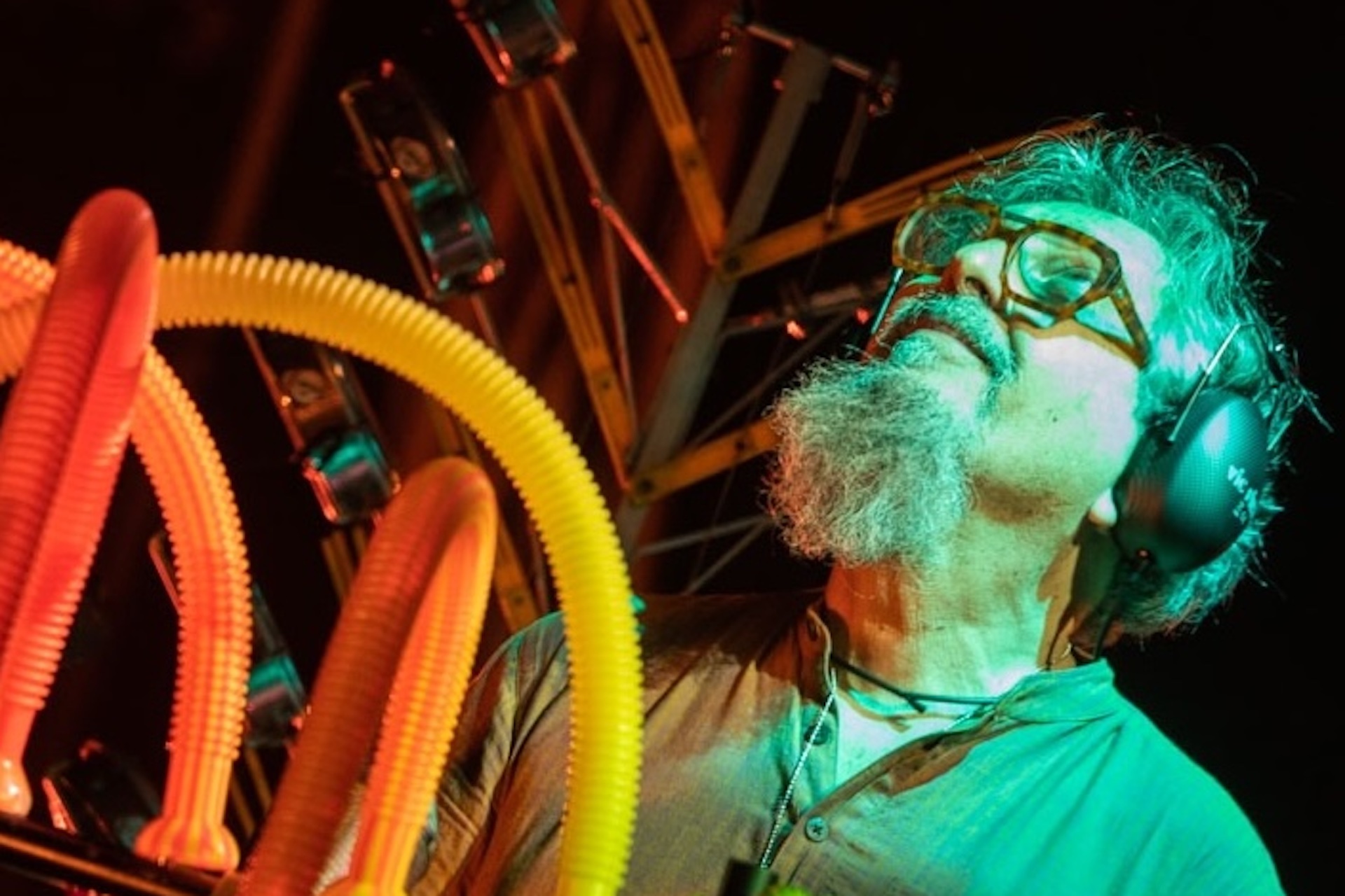 A black and white photo of a woman with dark curly hair in front of a pink and blue graphic