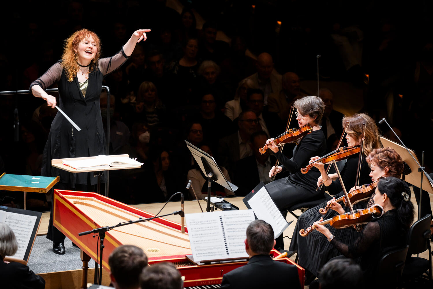 A woman sitting on a plush bench holding a cello