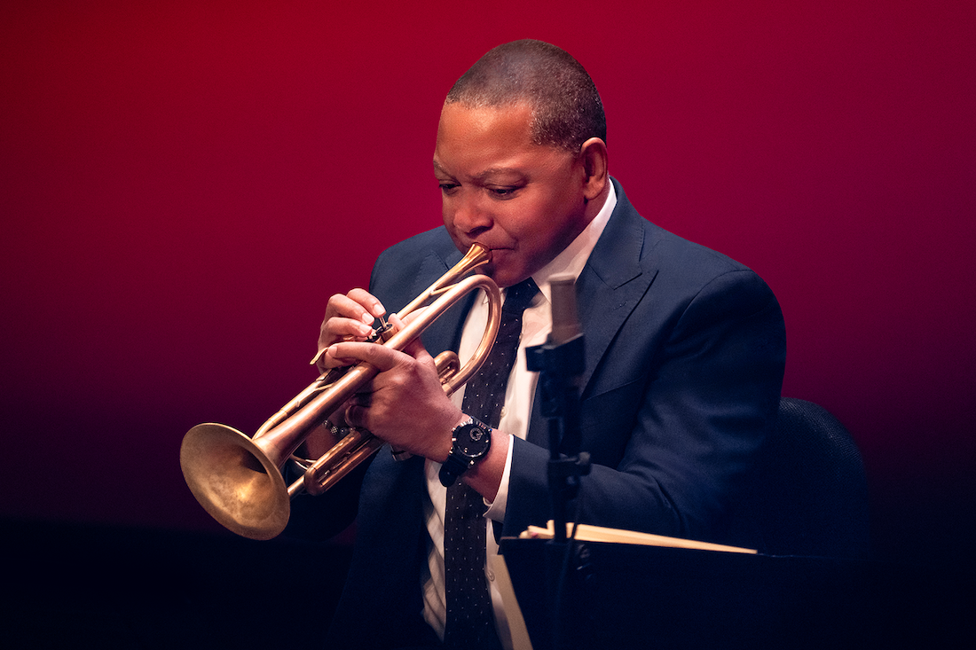 A man in a blue suit playing the trumpet