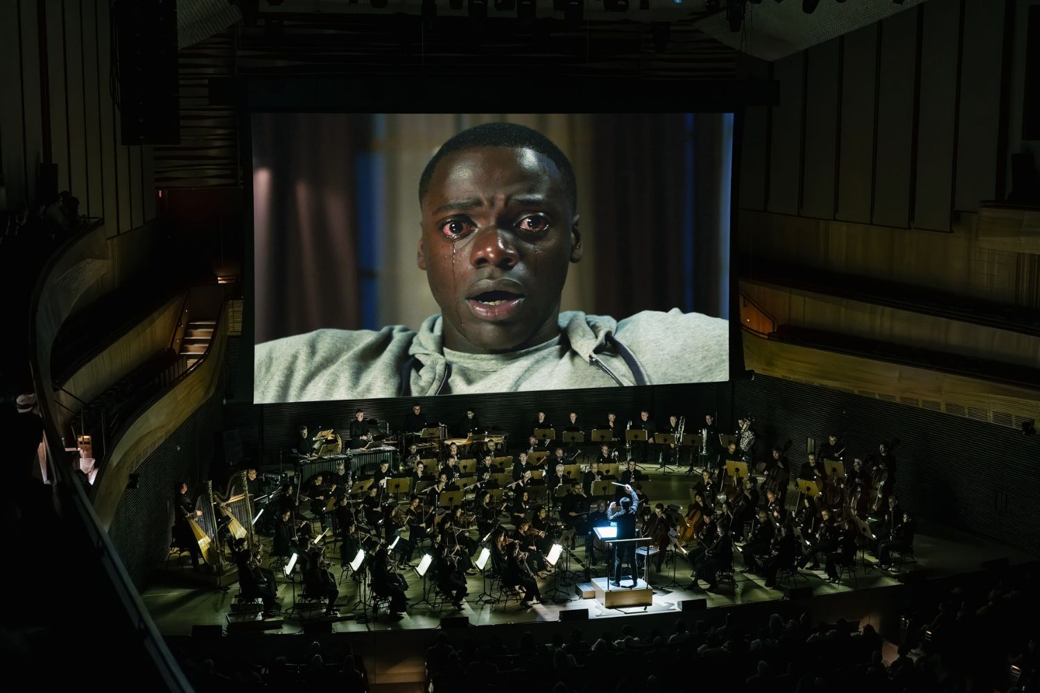 The New York Philharmonic playing in David Geffen Hall in front of a movie screen