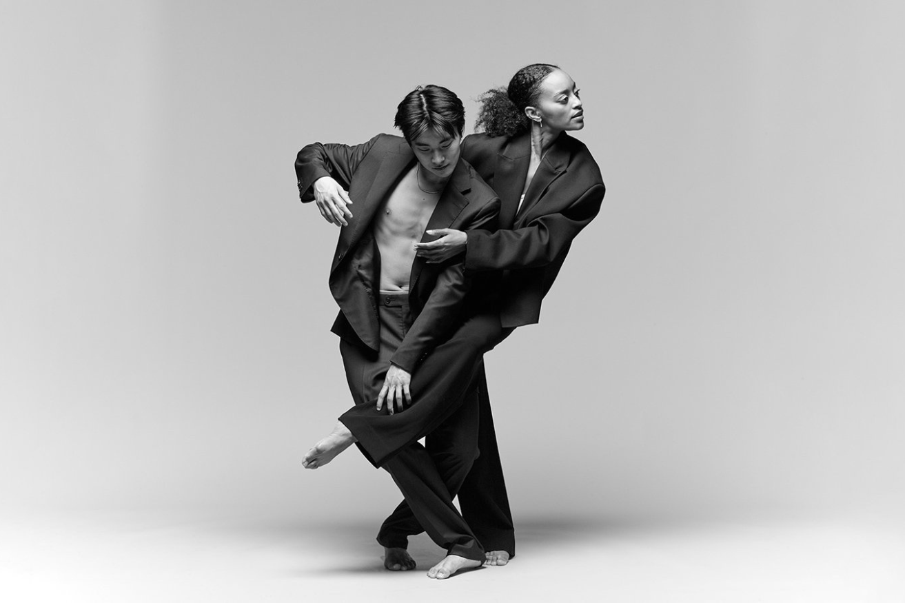A man in a yellow t-shirt laying on his side in front of a projected version of Hamlet