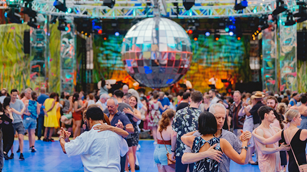 People dance in pairs under a disco ball