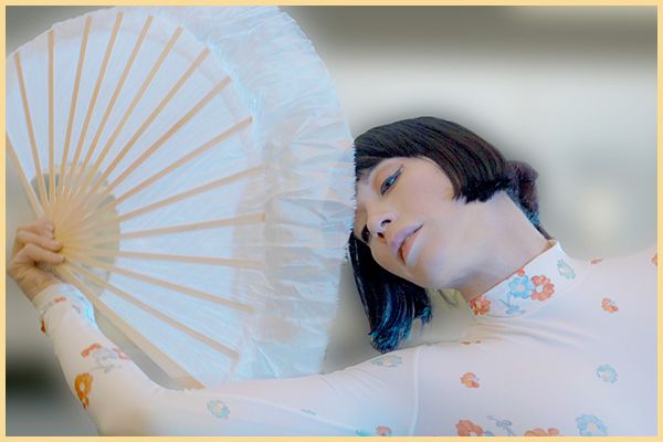 A woman holds a white fan