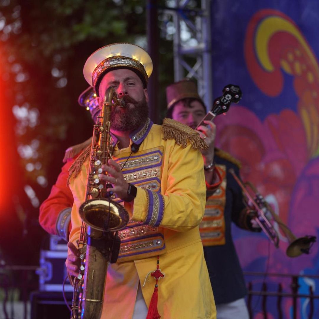 A man in a yellow suit playing the saxaphone