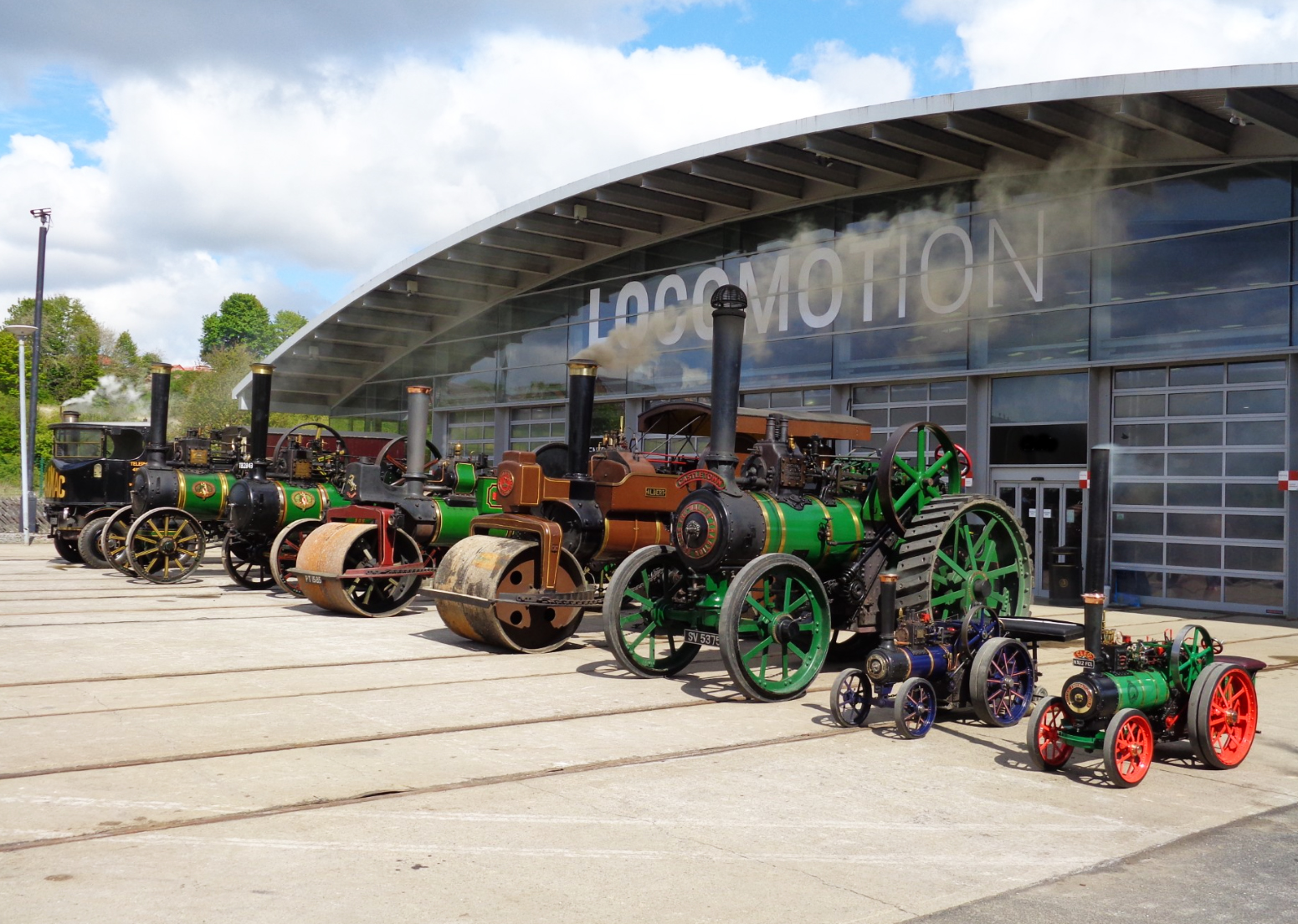 A garden featuring purple flowers with a museum building in the background against a bright blue sky with some clouds
