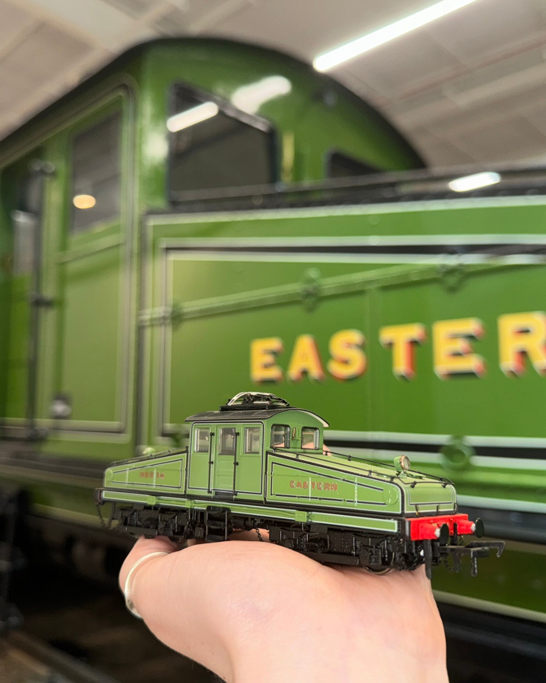 A hand holding a green model train