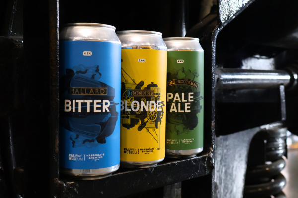 Three beer cans in blue, yellow and green with the words bitter, blonde and pale ale on the front