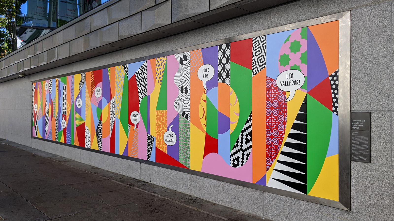 Photo: a brightly colored mural of geometric shapes and textures is pictured on a grey wall