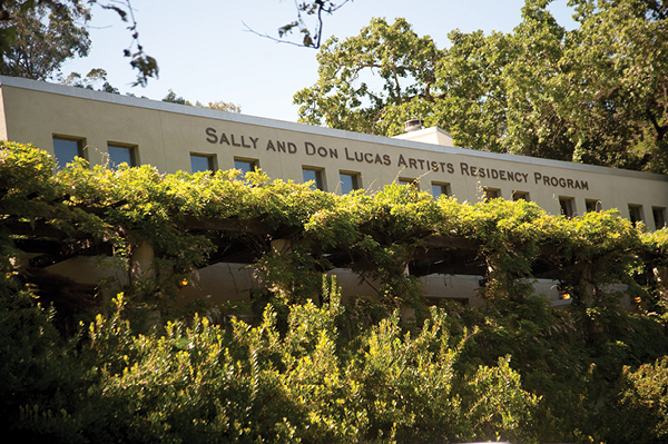 Image shows the building of a facade covered by foliage--the building facade has a sign that reads SALLY AND DON LUCAS ARTISTS RESIDENCY PROGRAM