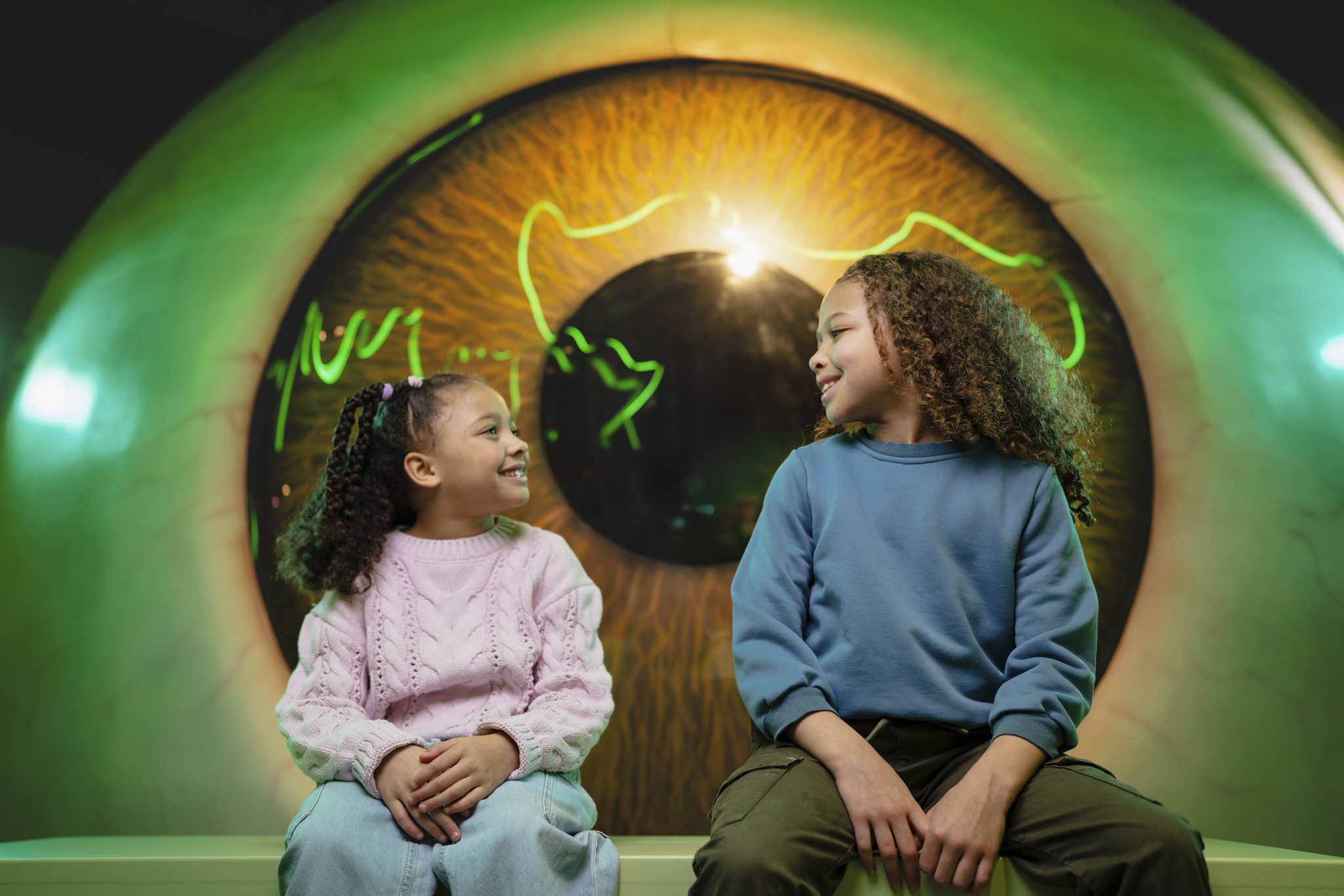 Brother and sister sitting in front of a giant eye