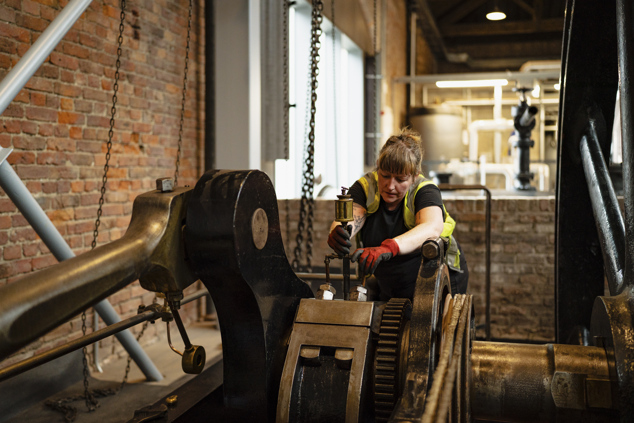 Museum technician cleaning a large object in Power Hall