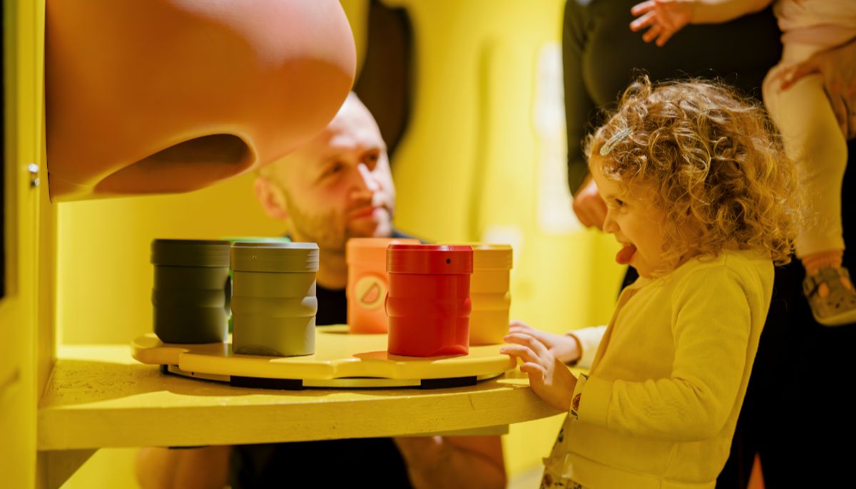 A young girl reacting to a smell interactive with a giant nose