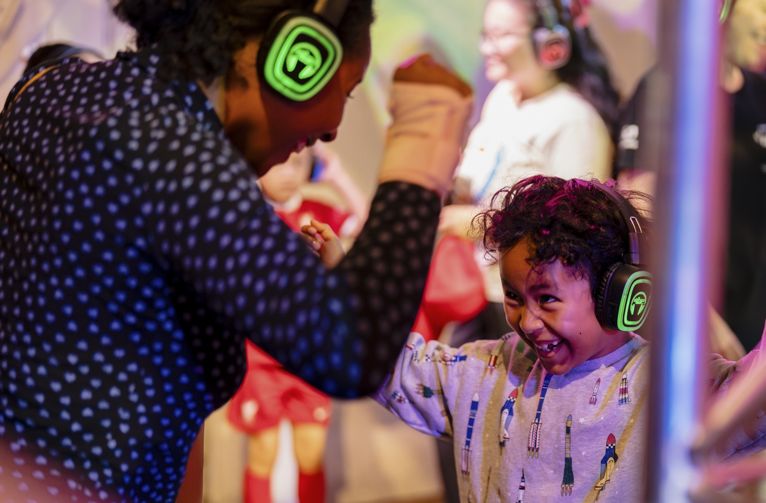 Mother and son dancing together with colourful headphones on